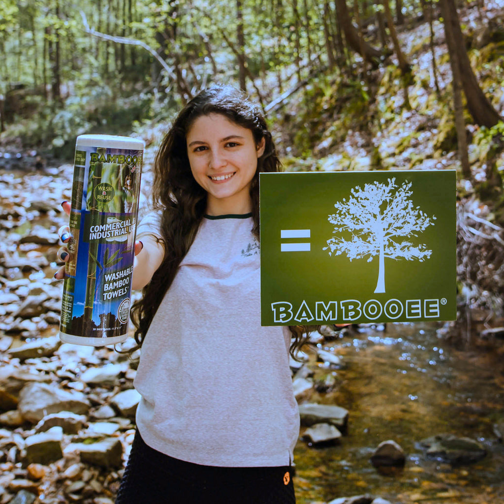 girl holding roll and picture of tree to represent the fact that we plant trees